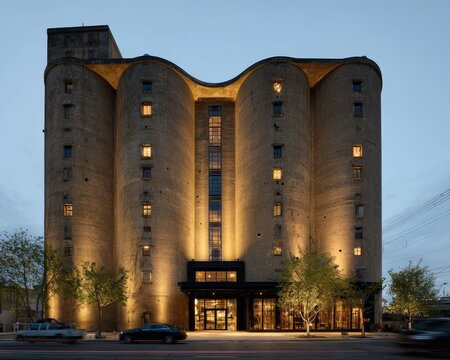 A repurposed silo building now a hotel. Warm lighting illuminates the exterior at dusk.