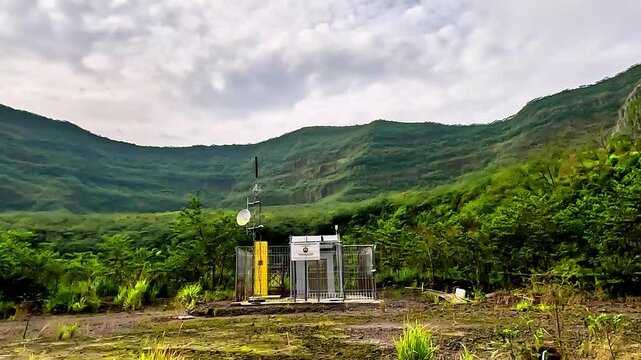 Volcanic monitoring equipment in the crater of Mount Kelud with a green mountain background.