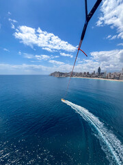 Benidorm, Spain - May 12, 2025: Midlife woman paragliding over the stunning coastline of Benidorm,...