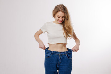 Happy Woman in Oversized Jeans Showing Weight Loss Results After Diet and Body Transformation