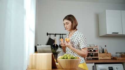 Caucasian mother prepare food for making salad while looking at food recipe in laptop at modern...