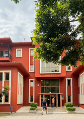 Visitors explore a vibrant red building with modern architecture in a sunny location