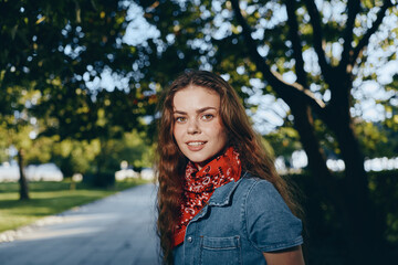 Lifestyle woman in modern boho-western denim street style wearing a red bandana outdoors with...