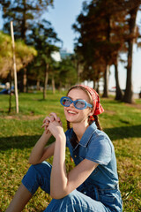 Lifestyle woman in modern boho-western denim street style sitting outdoors with bright blue...