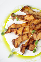 vegetarian dish fried mushrooms on the grill in a white plate close-up view