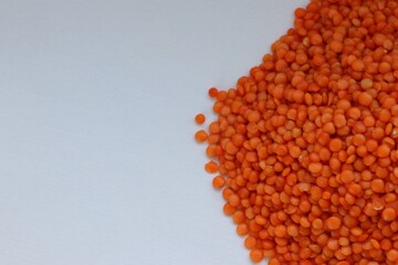 Scattered red lentils on white background — concept of natural plant-based protein, healthy eating and minimalist food styling