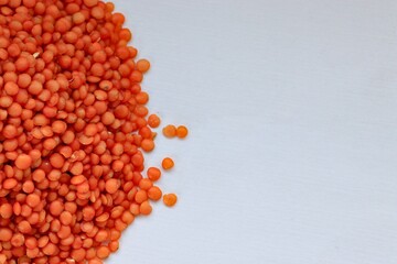 Scattered red lentils on white background — concept of natural plant-based protein, healthy eating and minimalist food styling