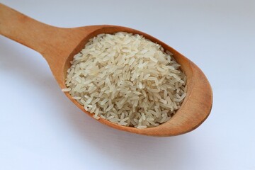 White rice in a wooden spoon on white background, close-up — concept of natural nutrition, visual purity and culinary simplicity for healthy lifestyle