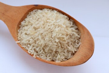 White rice in a wooden spoon on white background, close-up — concept of natural nutrition, visual purity and culinary simplicity for healthy lifestyle