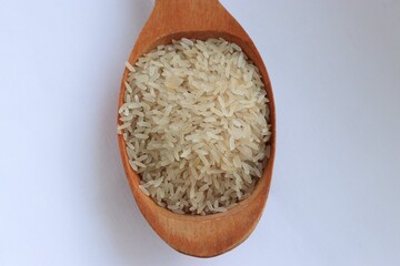 White rice in a wooden spoon on white background, close-up — concept of natural nutrition, visual purity and culinary simplicity for healthy lifestyle