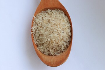 White rice in a wooden spoon on white background, close-up — concept of natural nutrition, visual purity and culinary simplicity for healthy lifestyle