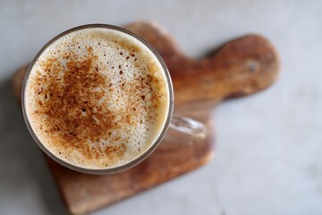 A frothy latte with cinnamon spice, presented on a rustic wooden board, capturing a cozy and delicious moment.