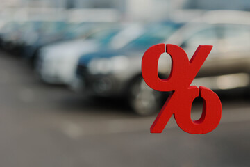 Row of new cars for sale and red percent sign. Buying a new car in car dealership