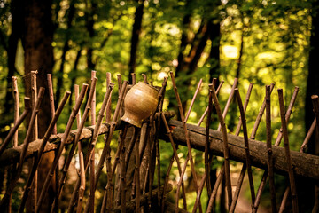 Decorative wooden cup resting on rustic fence in serene forest atmosphere during golden hour