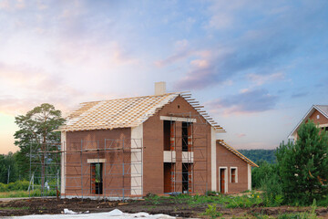 Construction of roof for two-story brick house, scaffolding for laying wooden frame.