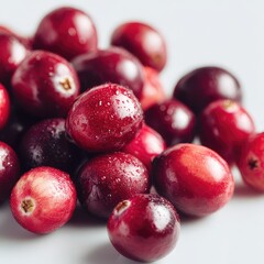 Fresh, juicy cranberries laid out on a clean white surface in close-up, showcases their bright color and shiny texture
