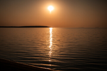 The sun sets over the calm water, a beautiful scene of peace and tranquility. A tranquil sunset...