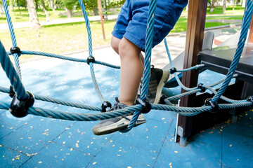 Little toddler kid child boy having fun leisure games passing obstacle course rope adventure park...