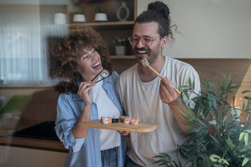 Happy couple enjoying sushi together in modern kitchen