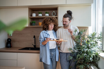 Young couple eating sushi in modern kitchen
