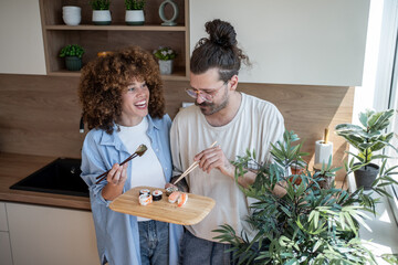 Happy couple eating sushi in modern kitchen