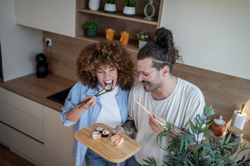 Happy couple enjoying sushi in modern kitchen