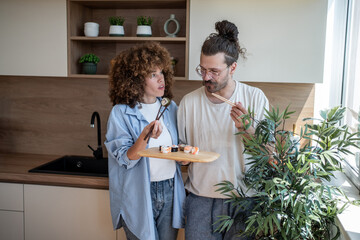 Young couple eating sushi with chopsticks in modern kitchen