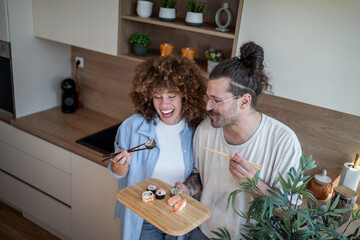 Happy couple enjoying sushi together in modern kitchen