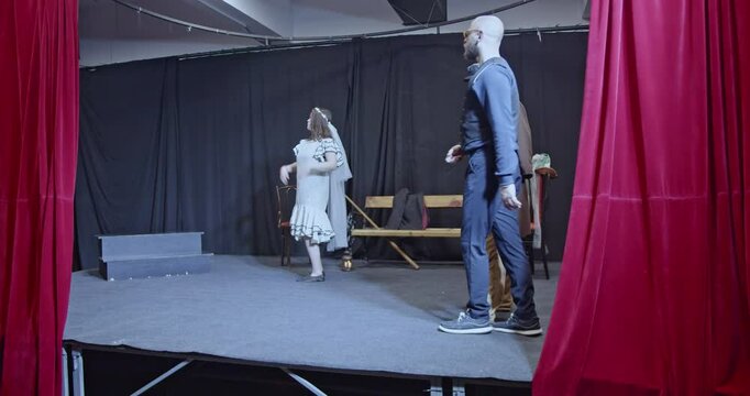Young actors rehearse a play on stage. A director gives instructions and guides their performance.