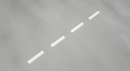 Minimalist road marking background with white dashed line on gray asphalt surface creating a sense of movement and direction