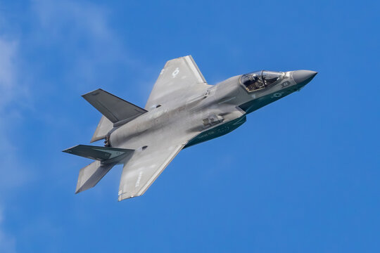 F-35 Lightning II Banking in Clear Blue Sky with Pilot Visible in Cockpit