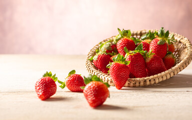 Strawberries, straw basket with beautiful strawberries on white rustic wooden surface, abstract...