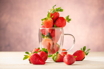 Strawberries in a mug, a glass mug with beautiful strawberries on a white rustic wooden surface,...