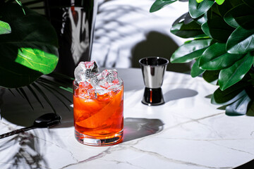 refreshing non-alcoholic negroni mocktail with alternative gin and red vermouth served over ice in...