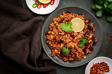 Mexican Chili dish with minced beef, beans, paprika, corn, cilantro, jalapeno pepper in tomato sauce, top view