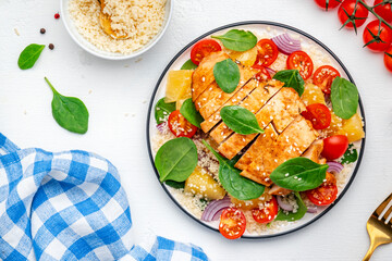Salad with chicken fillet, couscous, cherry tomatoes, red onion, fresh spinach and orange slices, top view