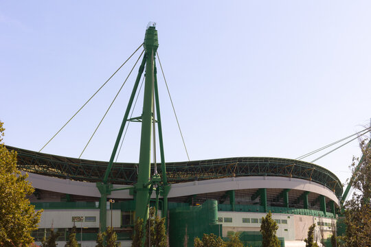 Modern sports stadium with green structural beams and curved roof on a clear day