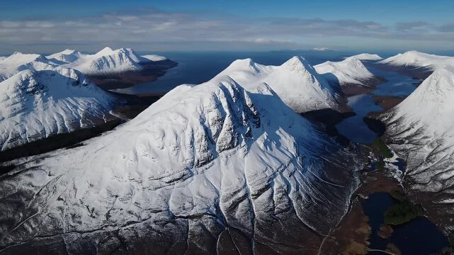 snow covered mountains and scenic loch captured via drone above Glencoe and Loch Leven region showing pristine winter beauty and tranquil alpine views perfect for travel videos or seasonal
