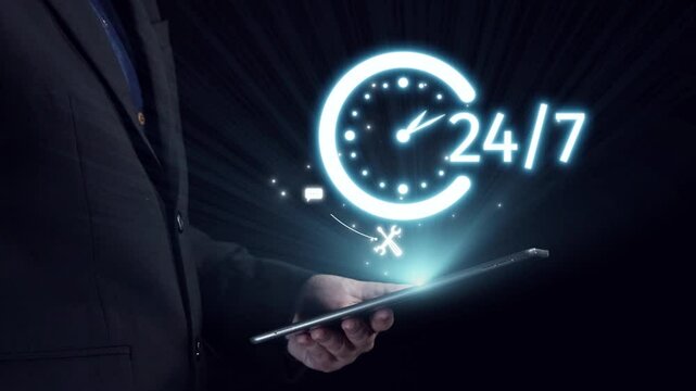 A businessman holds a tablet featuring glowing 24 hour service icons, representing constant availability and support in communication. The dark background enhances the visual impact. Qubit