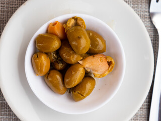Light and nutritious snack awaits, consisting of handful of pickled green pitted olives and slice of wholesome bran bread.