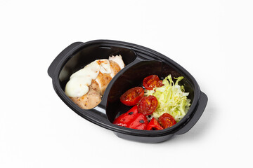 Baked chicken fillet with cheese, stewed tomatoes, bell pepper, and fresh cabbage on a plate against a white background