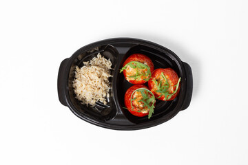 Stuffed baked tomatoes with boiled rice on a plate against a white background
