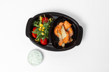 Red fish skewers with tomatoes, arugula, corn, and tartar sauce on a plate against a white background