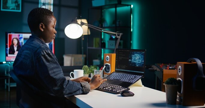 AI professional in home office using laptop to write programming language code. Artificial intelligence engineer working from home using notebook device to build application, camera B