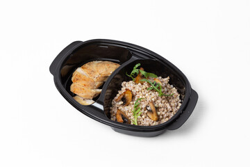 Buckwheat with sautéed mushrooms and baked chicken fillet on a plate against a white background