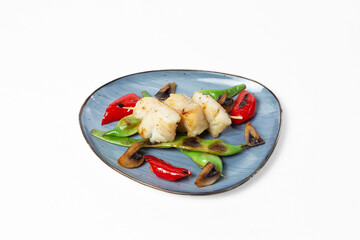 Grilled white fish skewers with sautéed mushrooms, bell pepper, and green beans on a plate against a white background