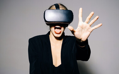 Woman wearing virtual reality glasses. Augmented reality game, future technology. Amazed girl in VR glasses touching something during VR experience. Virtual reality headset. Young girl in 3d goggles.