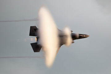 Modern fighter jet flying fast causing a vapor cone.