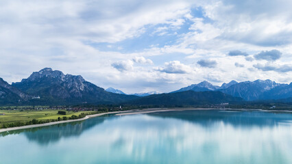 Puffy clouds gather above still lake waters and distant mountains.