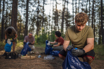 family of volunteers men woman pick up waste garbage to clean forest